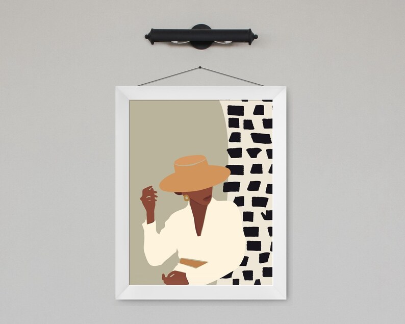 May include: A framed illustration of a person wearing a tan hat and a white shirt, standing in front of a black and white geometric pattern.