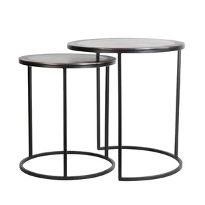 Pode incluir: Duas mesas laterais encaixáveis. As mesas têm tampos redondos de cor bronze e estruturas de metal preto. As pernas são retas e as bases são circulares. As mesas têm alturas diferentes, sendo uma ligeiramente menor que a outra.