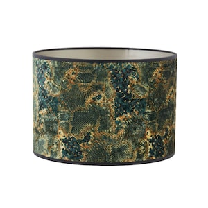 Może przedstawiać: Abażur lampy w zielono-złotym wzorze z czarną lamówką. Abażur ma wzór skóry węża.