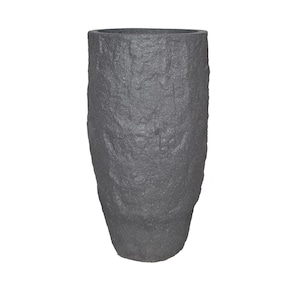 Könnte beinhalten: Eine hohe, dunkelgraue, strukturierte Vase mit einem rauen, steinartigen Aussehen. Die Vase hat eine zylindrische Form mit leicht verjüngtem Boden und einer breiten Öffnung oben. Die Oberfläche hat eine raue, unebene Textur.