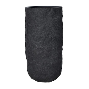 Könnte beinhalten: Eine hohe, zylindrische, schwarze Vase mit einer strukturierten, steinartigen Oberfläche. Die Vase hat eine breite Öffnung und einen abgerundeten Boden. Die dunkle Farbe und die raue Textur verleihen ihr eine rustikale, natürliche Ästhetik.