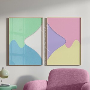 May include: A modern living room scene featuring a pink armchair, two framed abstract art pieces, and a mint green side table with a lamp. The artwork has pastel colors, and the room is decorated with a patterned rug.