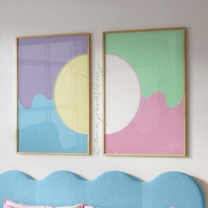 May include: A bedroom scene featuring a light blue scalloped headboard, pink and white pillows, and a mint green comforter. Two framed abstract art prints with pastel colors hang above the bed. A copper-colored pendant light hangs from the ceiling.