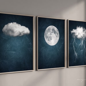May include: Three framed prints with a dark blue background. The first print features a white cloud, the second print features a white moon, and the third print features a white cloud with white lightning bolts.