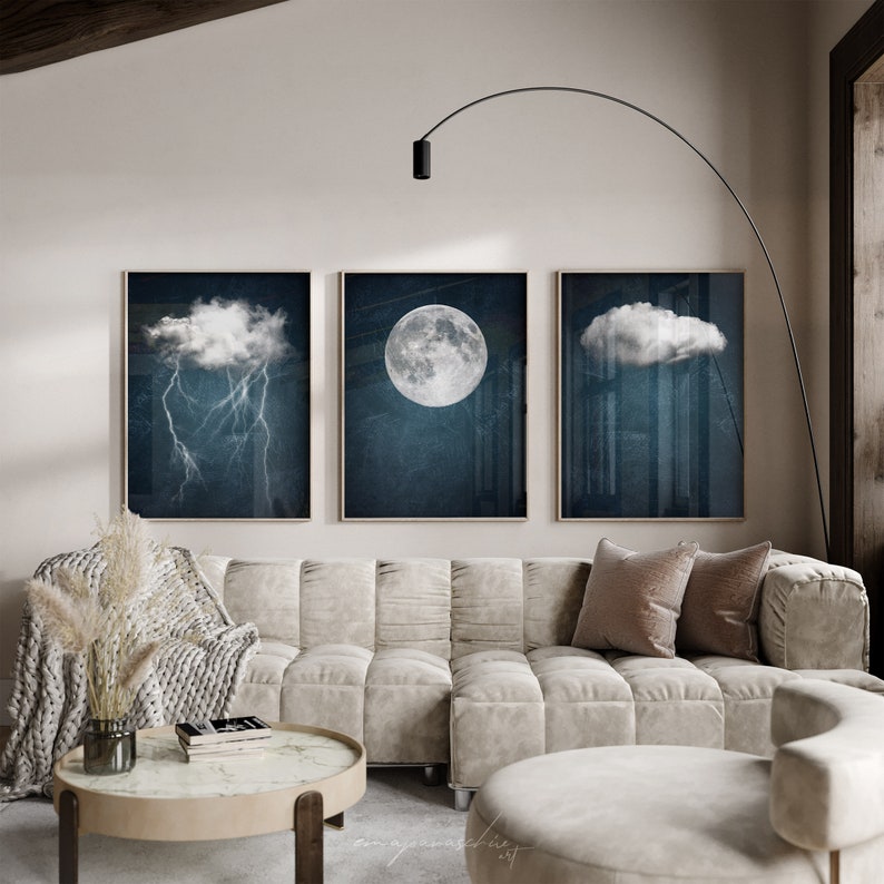 May include: Three framed prints of a moon, a cloud, and a cloud with lightning. The prints are hanging on a white wall above a white couch with pillows.