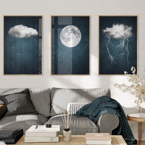 May include: Three framed prints with a dark blue background and white clouds. The center print features a full moon, while the left and right prints feature clouds with rain and lightning, respectively.