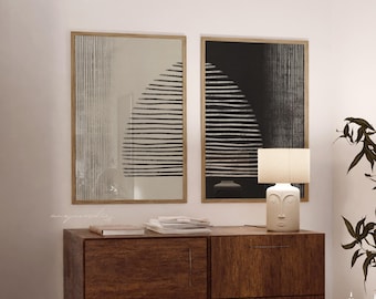 May include: Two framed abstract art prints with a minimalist design. One print features a beige background with black lines, the other a black background with white lines. The prints are displayed above a wooden cabinet.