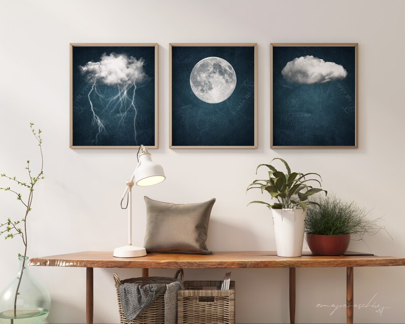 May include: Three framed prints with a dark blue background and white clouds. The left print features a cloud with lightning bolts. The middle print features a full moon. The right print features a cloud.