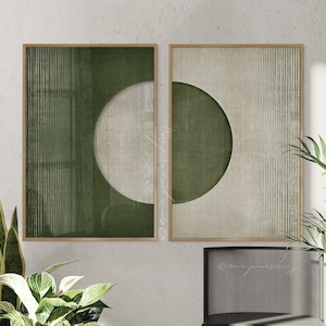 May include: Two framed abstract art prints. One print features a green circle and vertical lines, the other has a half-circle and vertical lines. The prints have a neutral color palette with green and beige tones. The frames are made of light-colored wood.