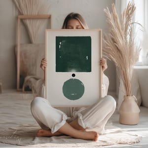 Peut inclure: Une impression d'art abstrait encadr&eacute;e avec un carr&eacute; et un cercle verts sur un fond blanc. L'impression est tenue par une personne.