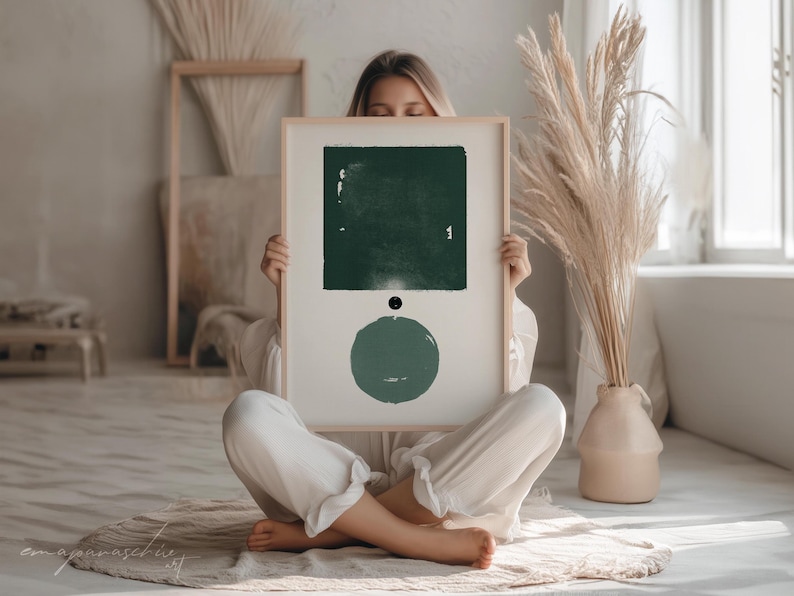 Peut inclure: Une impression d'art abstrait encadr&eacute;e avec un carr&eacute; et un cercle verts sur un fond blanc. L'impression est tenue par une personne.