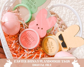 May include: A white basket filled with colorful Easter-themed playdough containers and bunny-shaped tags. The tags have the text "Have a Won-Doh-Ful Easter" and "Happy Easter".