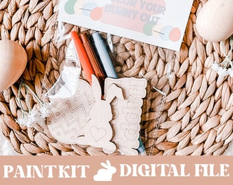 May include: A clear plastic bag contains a wooden Easter egg, bunny-shaped cutouts, and markers. A card with the text "Happy Easter Day Color Your Bunny Out" is visible. The words "Paintkit Digital File" are at the bottom.