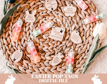 May include: A set of eight Easter-themed pop-it keychains with different designs and sayings. The keychains are made of clear plastic with colorful bubbles and are attached to wooden tags with various Easter greetings. The keychains are displayed on a woven basket.
