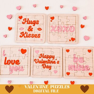 May include: Set of five Valentine's Day jigsaw puzzles with pink and red hearts and phrases like "Hugs & Kisses", "XOXO", "I Love You", "Happy Valentine's Day", and "Be Mine".