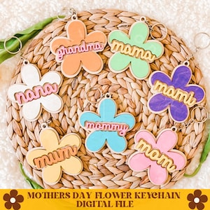 May include: Set of seven colorful flower-shaped keychains with different names on each, including "mama", "nana", "mom", "momi", "mommy", "grandma", and "mum".