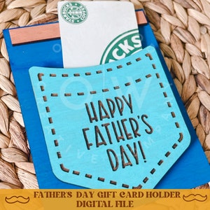 May include: A blue and brown wooden gift card holder with a pocket for a gift card. The pocket has a blue background with white stitching and the text "Happy Father's Day!" in brown lettering.