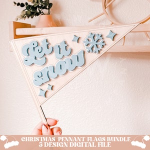 May include: A wooden pennant flag with the text "Let it snow" in blue script lettering. The flag also features a blue snowflake and two blue stars.