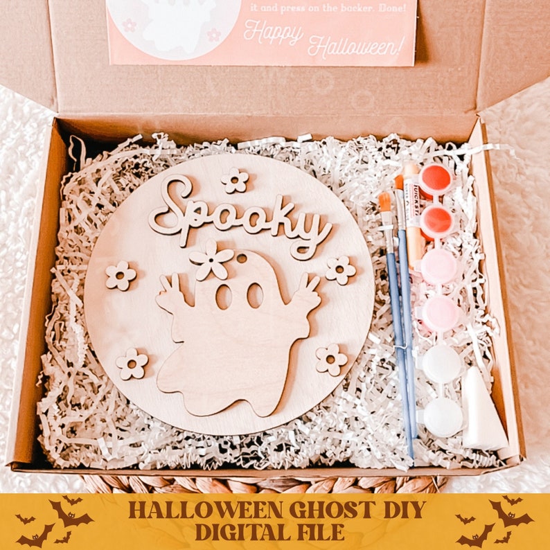 May include: A DIY craft kit featuring a wooden round sign with a ghost and the word "Spooky" painted on it. The kit includes paint, brushes, and a small wooden ghost. The sign is in a box with shredded paper.