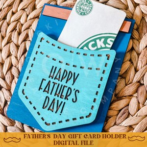 May include: A blue and turquoise wooden card holder with a pocket for a gift card. The holder has the text "Happy Father's Day!" on the front.