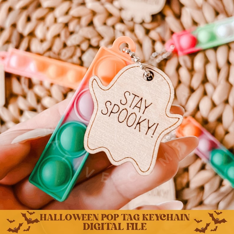 Op de afbeelding: Een Halloween-thema pop it sleutelhanger met een spookvormig houten label waarop "Stay Spooky!" staat. De pop it is groen, oranje en roze.