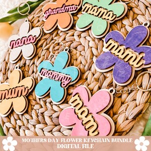 Puede incluir: Un conjunto de seis dise&ntilde;os de llaveros de flores de madera con diferentes colores y las palabras "mama", "momi", "mommy", "nana", "grandma" y "mum" en letras doradas.  Paquete de llaveros de flores para el D&iacute;a de la Madre Archivo digital.