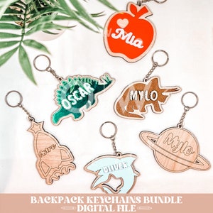 May include: A set of six wooden backpack keychains with different designs and names. The designs include an apple, a dinosaur, a triceratops, a rocket, a shark, and a planet. The names on the keychains are Mia, Oscar, Milo, Astro, Oliver, and Milo.
