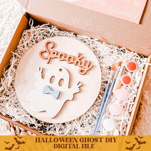 May include: A DIY Halloween ghost craft kit with a wooden circle, a ghost cutout, the word "Spooky" in cursive, and paint supplies in a box.