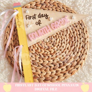 May include: A school pennant reading "First day of Fourth Grade" with star decorations. A yellow ruler with pink and white ribbons is attached. The pennant is on a woven, circular placemat.