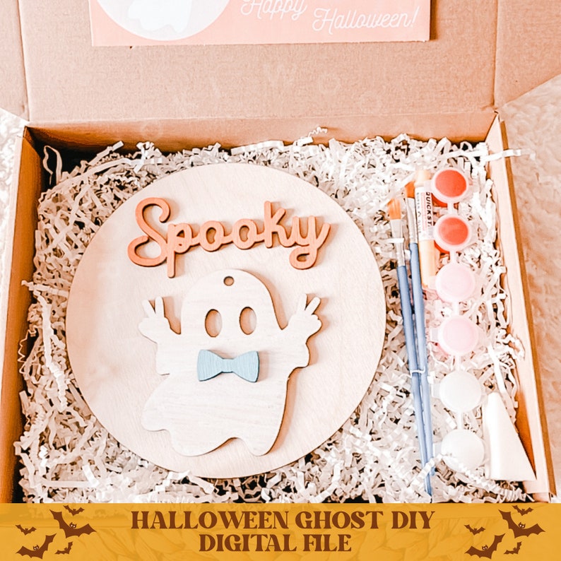 May include: A wooden craft kit with a ghost cutout, the word "Spooky" and paint supplies. The kit is in a brown box with white shredded paper.