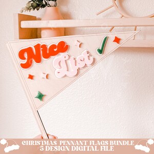 May include: A wooden Christmas pennant flag with the words "Nice List" in red and pink lettering. A green checkmark is in the upper right corner of the flag. The flag is decorated with red and green stars.