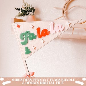 May include: A wooden pennant flag with the text "fa la la" in green, red, and pink letters. The flag is decorated with white stars and a green Christmas tree.