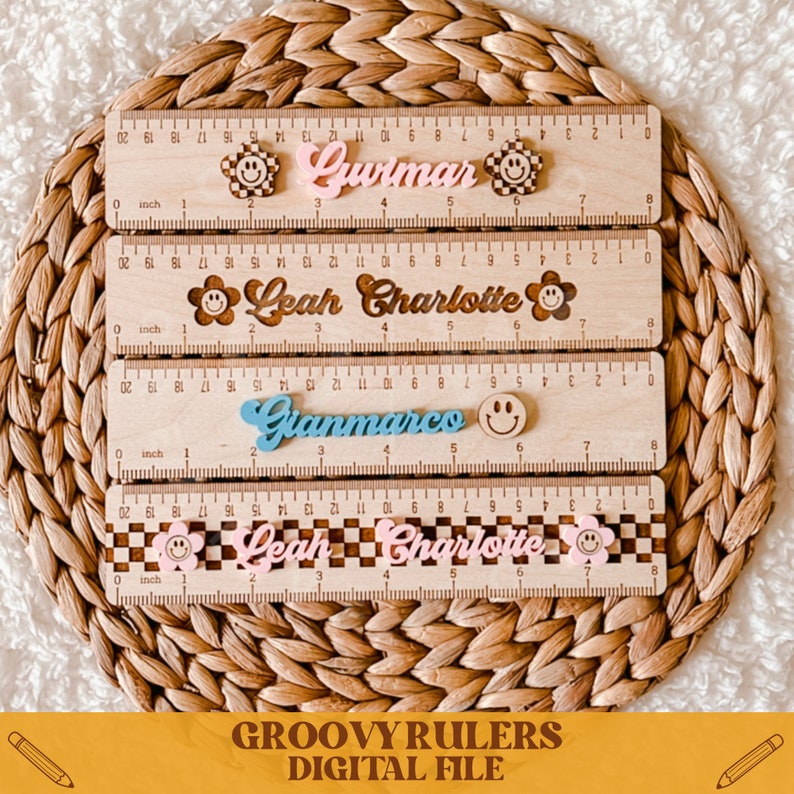 May include: Four wooden rulers with colorful smiley face stickers and personalized names. The names are "Gwimar", "Leah Charlotte", "Gianmarco", and "Leah Charlotte".