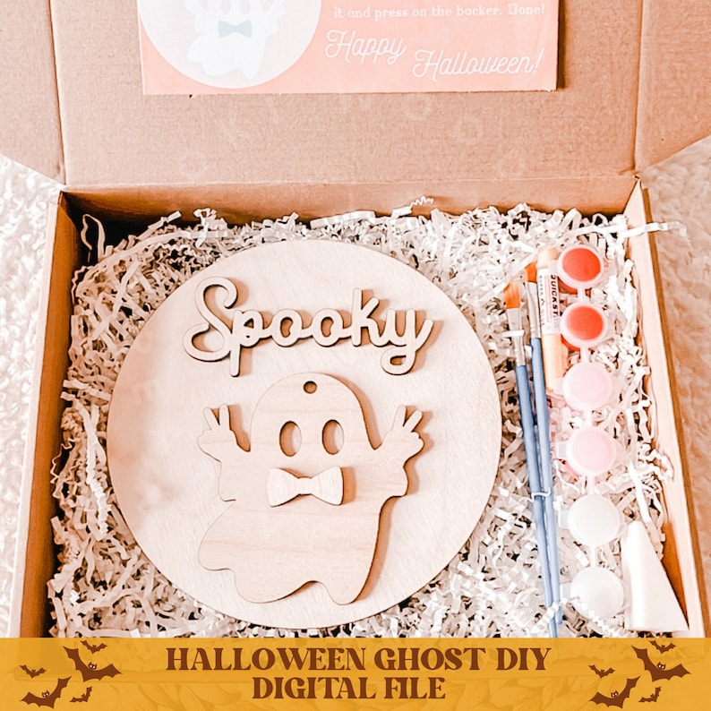 May include: A wooden craft kit with a round wooden base, a ghost cutout, and the word "Spooky" in cursive. The kit includes paint, brushes, and a small white cone. The text "Halloween Ghost DIY Digital File" is at the bottom of the image.