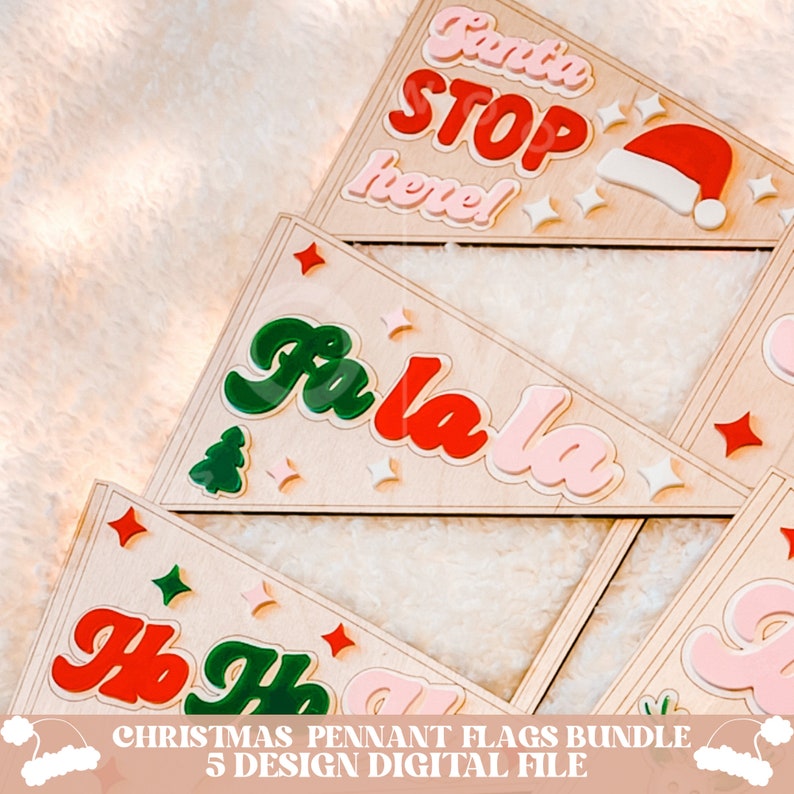 May include: A set of five Christmas pennant flags with different designs. The flags are made of wood and have a pink, red, green, and white color scheme. The designs include "Santa Stop Here!" with a Santa hat, "Fa La La", and "Ho Ho Ho".