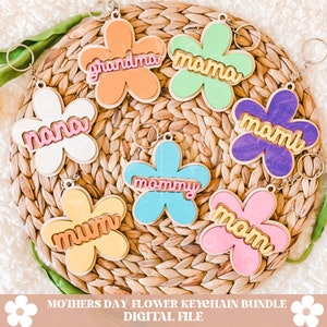 Puede incluir: Un conjunto de ocho llaveros de madera con forma de flor de colores con diferentes nombres, incluyendo "mama", "mommy", "grandma", "nana", "momi", "mum" y "mom".