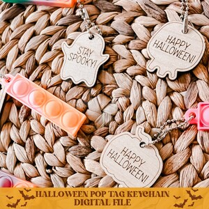 Op de afbeelding: Digitaal bestand voor een Halloween pop tag sleutelhanger. Het ontwerp bevat een houten pompoen met de tekst "Happy Halloween!" en een spook met de tekst "Stay Spooky!"
