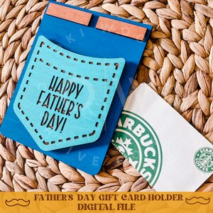 May include: A blue wooden pocket-shaped sign with the text "Happy Father's Day!" in white. A white gift card with a green Starbucks logo is displayed in the pocket.