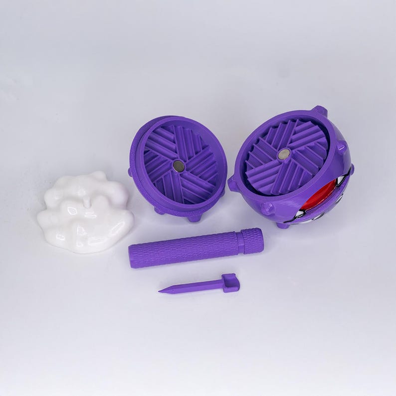 May include: A purple, 3D-printed Gengar-themed model kit, featuring two wheel-like components, a cylindrical piece, a small spike, and a white cloud-shaped piece. The Gengar component has a red interior and a smiling face.