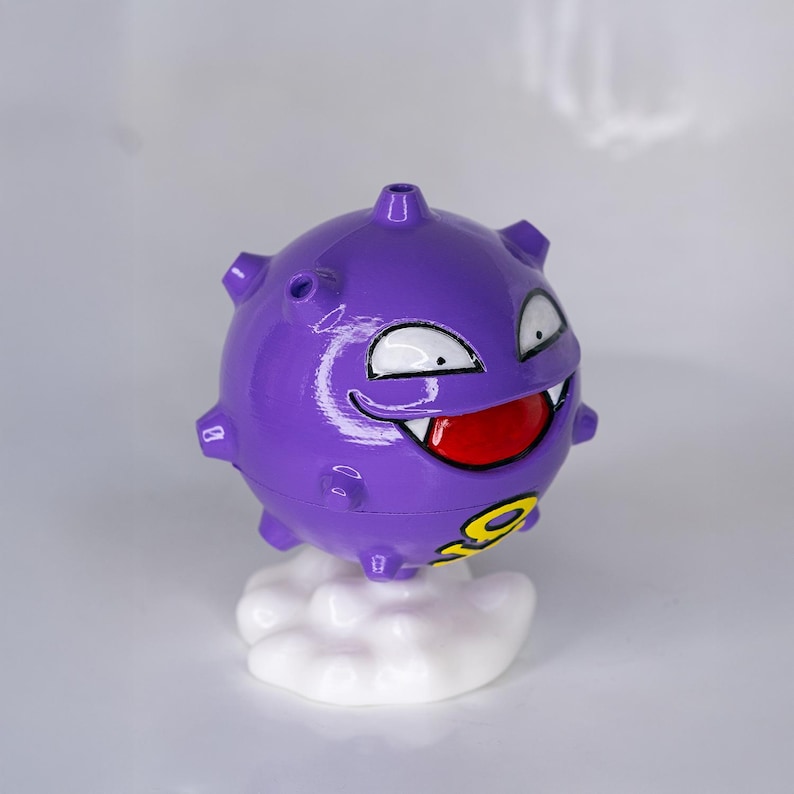 May include: A purple, spherical figure with a smiling face, white eyes, and a red mouth. The figure has small protrusions and sits atop a white cloud-shaped base. A yellow number 9 is visible on the figure.
