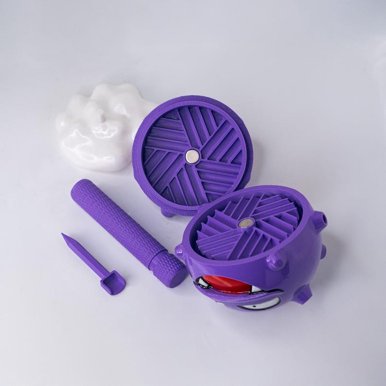 May include: A purple, multi-piece novelty item with a cartoon-like design. The set includes a cylindrical handle, a small tool, two circular components, and a spherical component with a face. The components are arranged on a white surface.