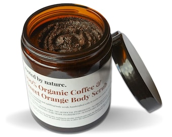 May include: A brown glass jar with a black lid filled with a dark brown coffee and orange body scrub. The jar has a white label with the text "Tooted by nature. 100% Organic Coffee & Sweet Orange Body Scrub" printed on it.