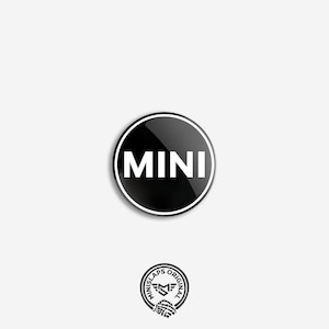 May include: A black and white MINI sticker featuring the word "MINI" in white, within a black circle with a white outline. Beneath is a smaller circular logo with text and a hand graphic.