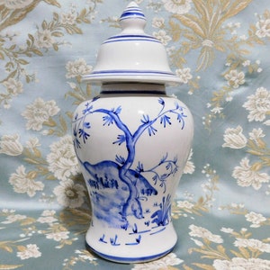 Op de afbeelding: Een witte keramische gemberpot met een blauw-wit bloemenmotief. De pot heeft een deksel met een blauwe streep rond de bovenkant.