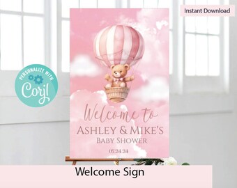 May include: Pink welcome sign with a teddy bear in a hot air balloon. The sign says "Welcome to Ashley & Mike's Baby Shower 07.24.24".