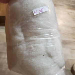 May include: A clear plastic bag filled with white fiberfill. A white label with the text "4 oz" is attached to the bag.