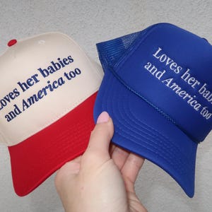 embroidered royal blue foam/ canvas cream and red hat that says Loves her babies and America too