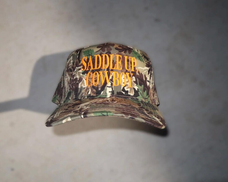 camo trucker hat, hat cowboy snapback, snapback cap country, country western cap, cap woodland hunting, hunting headwear orange, orange embroidered hat, hat rodeo style, style rustic hunting, hunting camouflage baseball, baseball hat outdoor, outdoor ranch accessory, saddle up cowboy