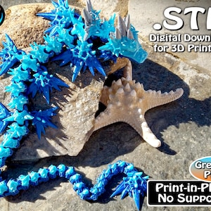 May include: A blue and light blue articulated dragon model with spiky details, designed for 3D printing. The image includes the text ".STL Digital Download for 3D Printing" and "Print-in-Place No Supports". A starfish is also present.