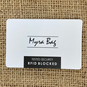 May include: White card with black text that reads "Myra Bag" and "TESTED SECURITY RFID BLOCKED".